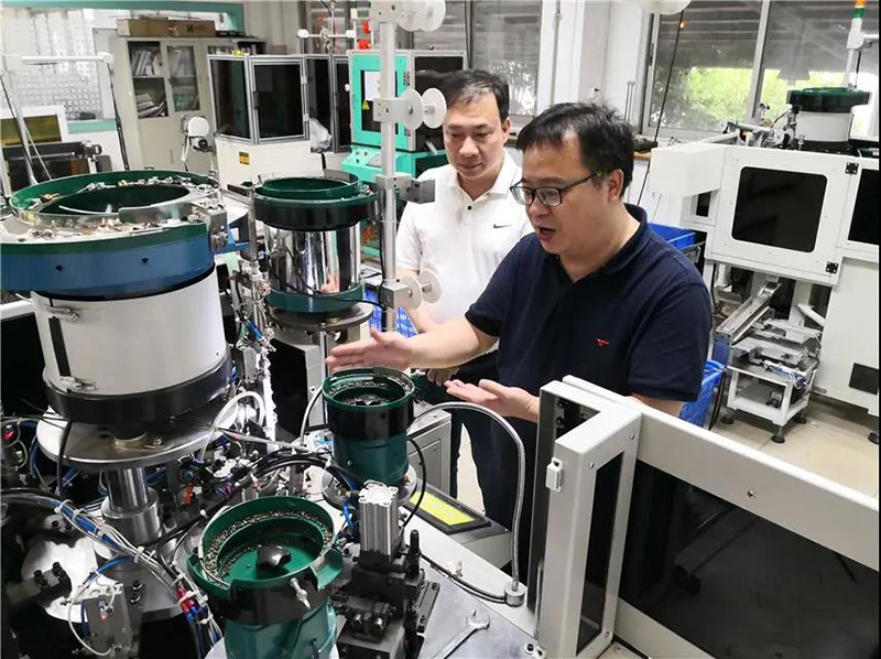 華圣達技術設備中心研發人員(右)在介紹自主研發的智能生產拉鏈機械設備 華圣達技術設備中心研發人員(右)在介紹自主研發的智能生產拉鏈機械設備